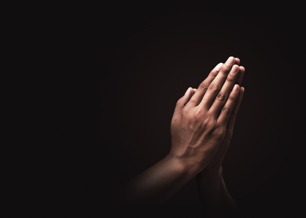 Imagine cu două mâini în poziție de rugăciune pe un fundal negru