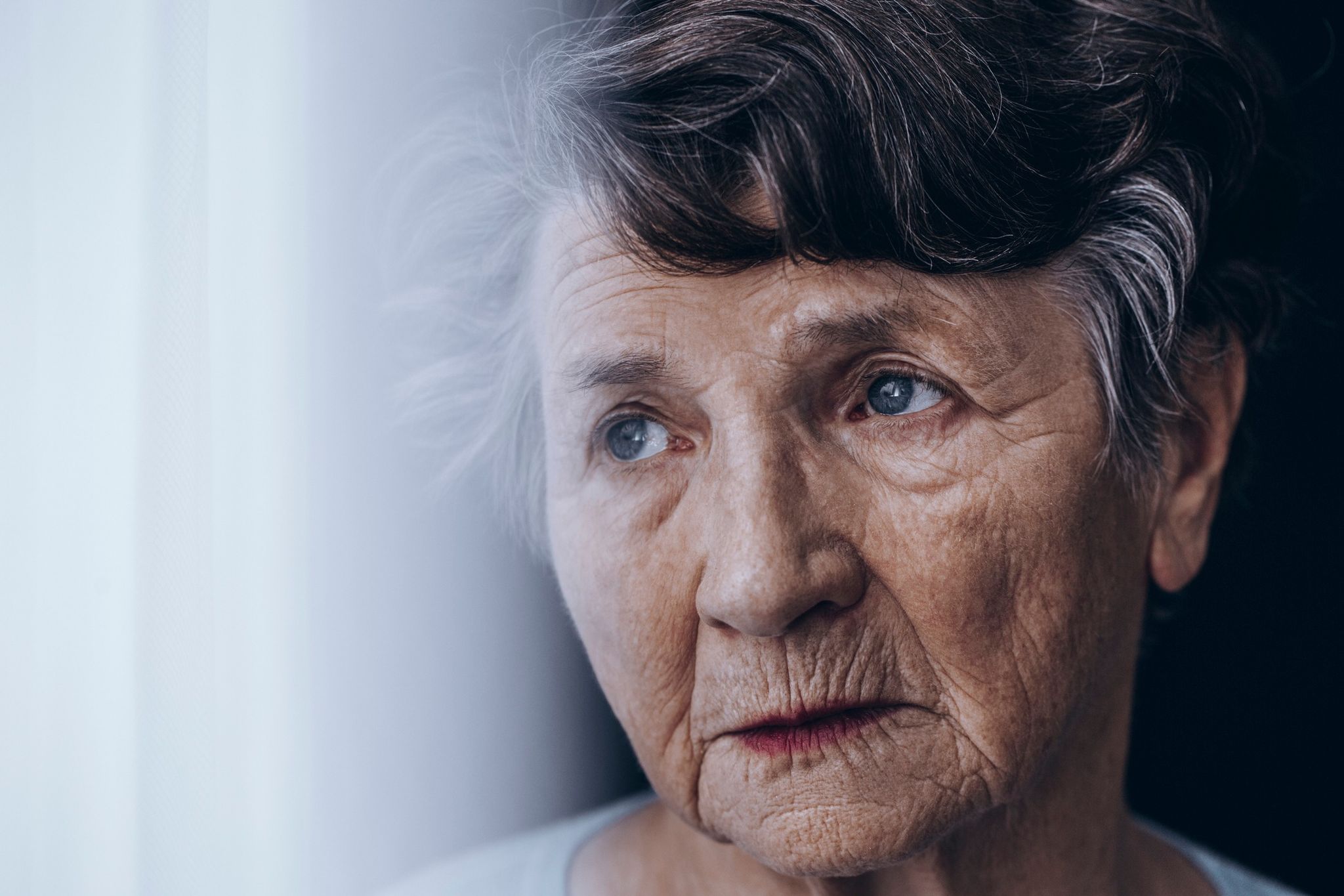 Imagine cu o femeie bătrână care se uită pe fereastră