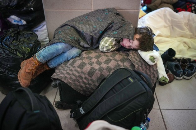 Imagine din Zahony, Ungaria cu un copil refugiat care doarme pe bagajele familiei sale în gară, după ce a călătorit cu trenul