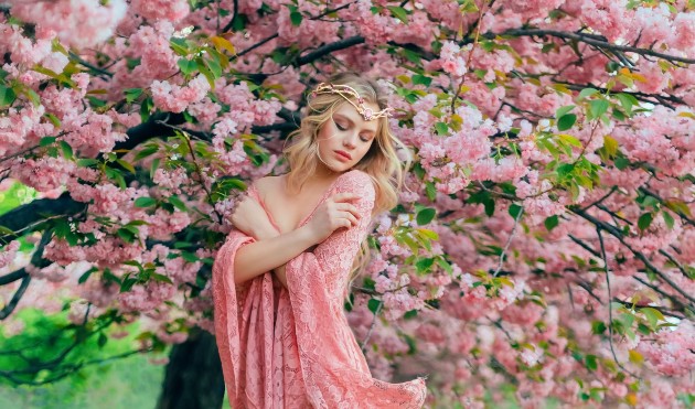 Imagine cu o prințesă îmbrăcată în roz care stă lângă un copac cu flori roz