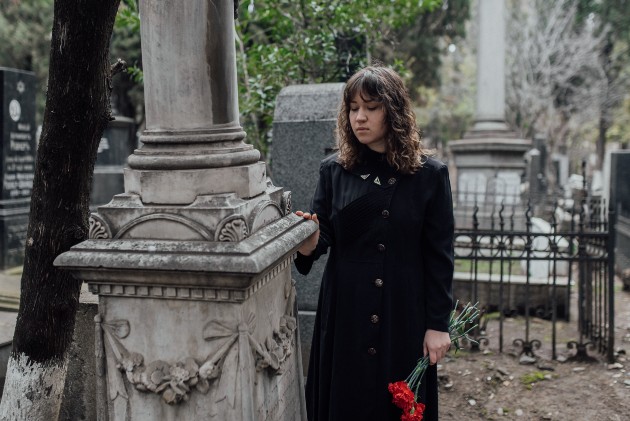 Imagine cu o fată îmbrăcată în negru lângu un cimitir