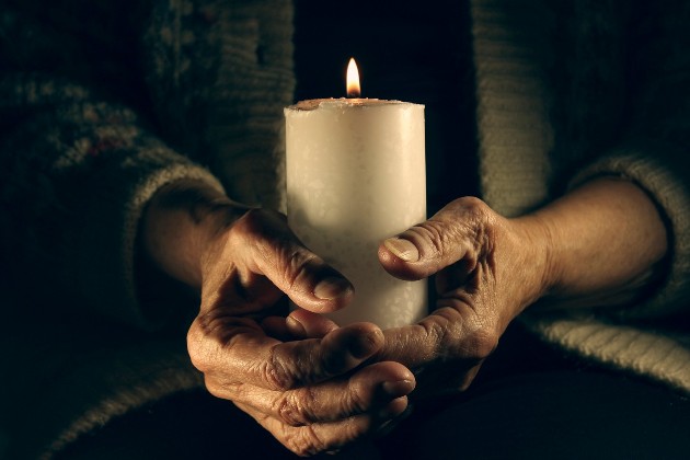 imagine cu mâini de femie care țin o lumânare albă