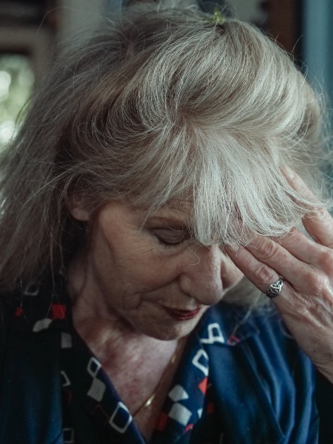 Imagine cu o femeie în vârstă care este supărată și ține mâna la ochi