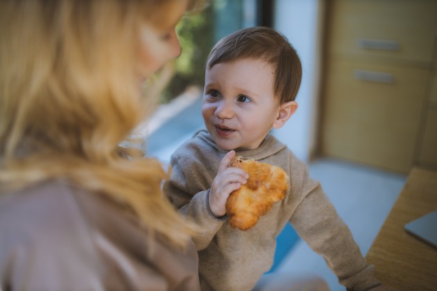 Imagine cu un bebeluș care mănâncă un croissant