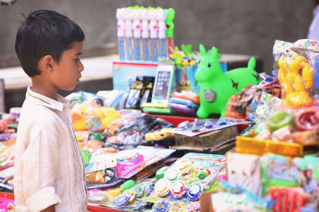 Imagine cu un băiețel indian care cumpără jucării dintr-un magazin de jucării