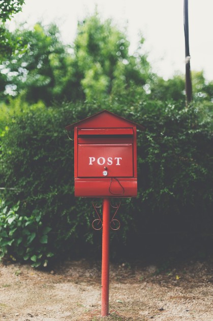 Imagine cu o cutie poștală roșie în fața unei case