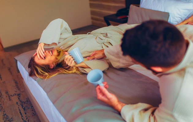 Imagine cu o femeie și un bărbat care stau în pat și râd