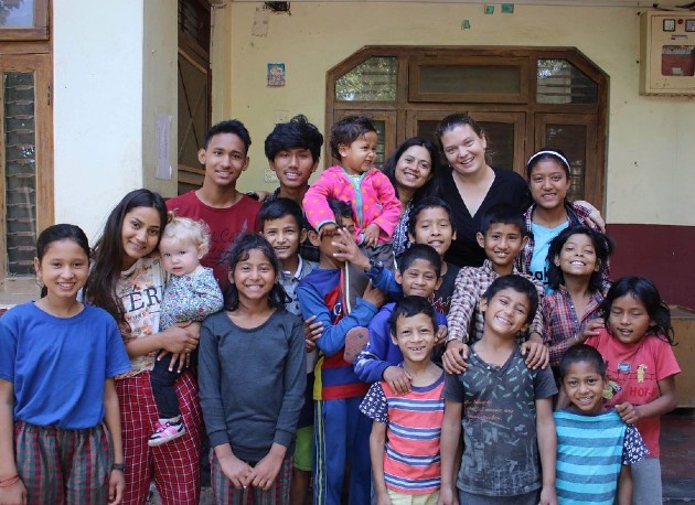 Imagine cu Maggie Doyne alături de copii nepalezi și femei nepaleze