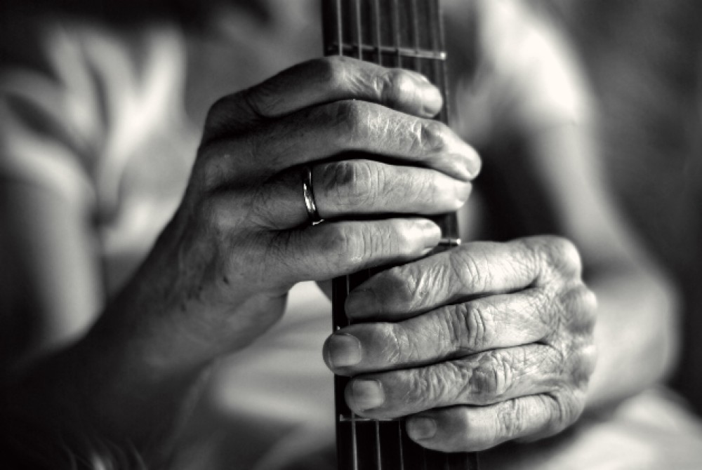 Imagine alb-negru cu un bărbat care ține o chitară în mână