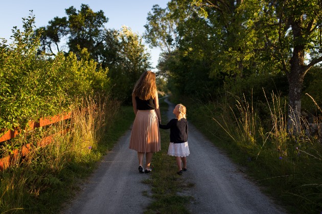 Imagine cu o femeie și o fetiță care se plimbă pe o alee