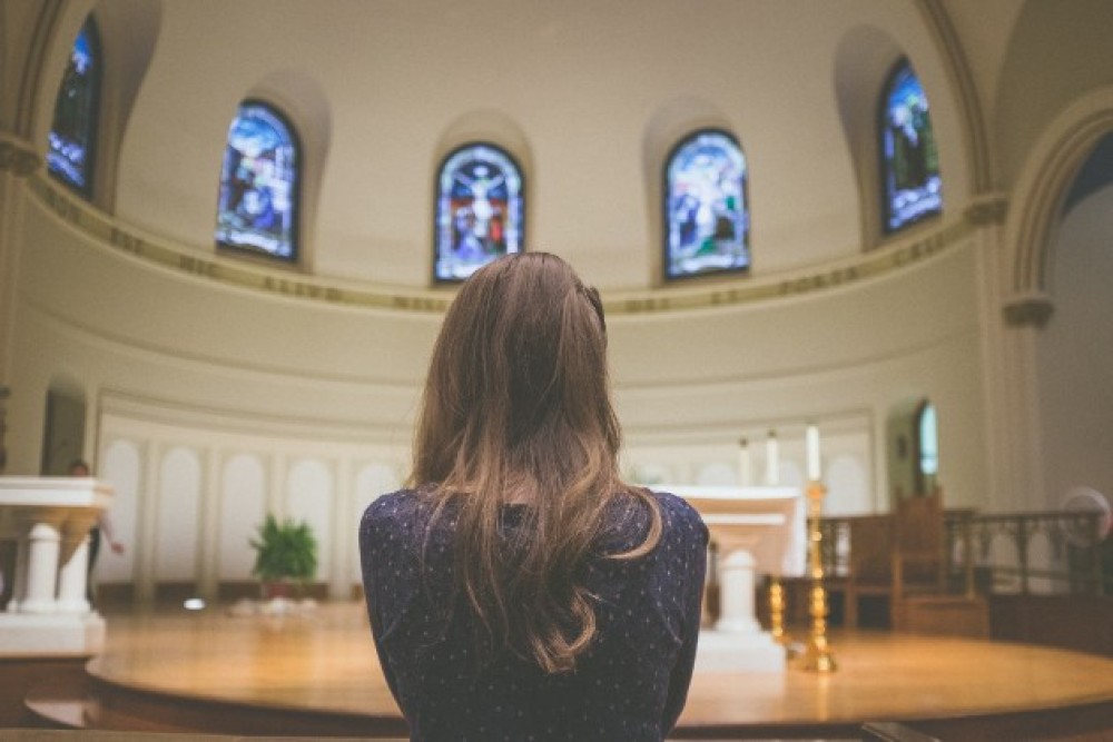 Imagine de la spate cu o femeie care stă în biserică