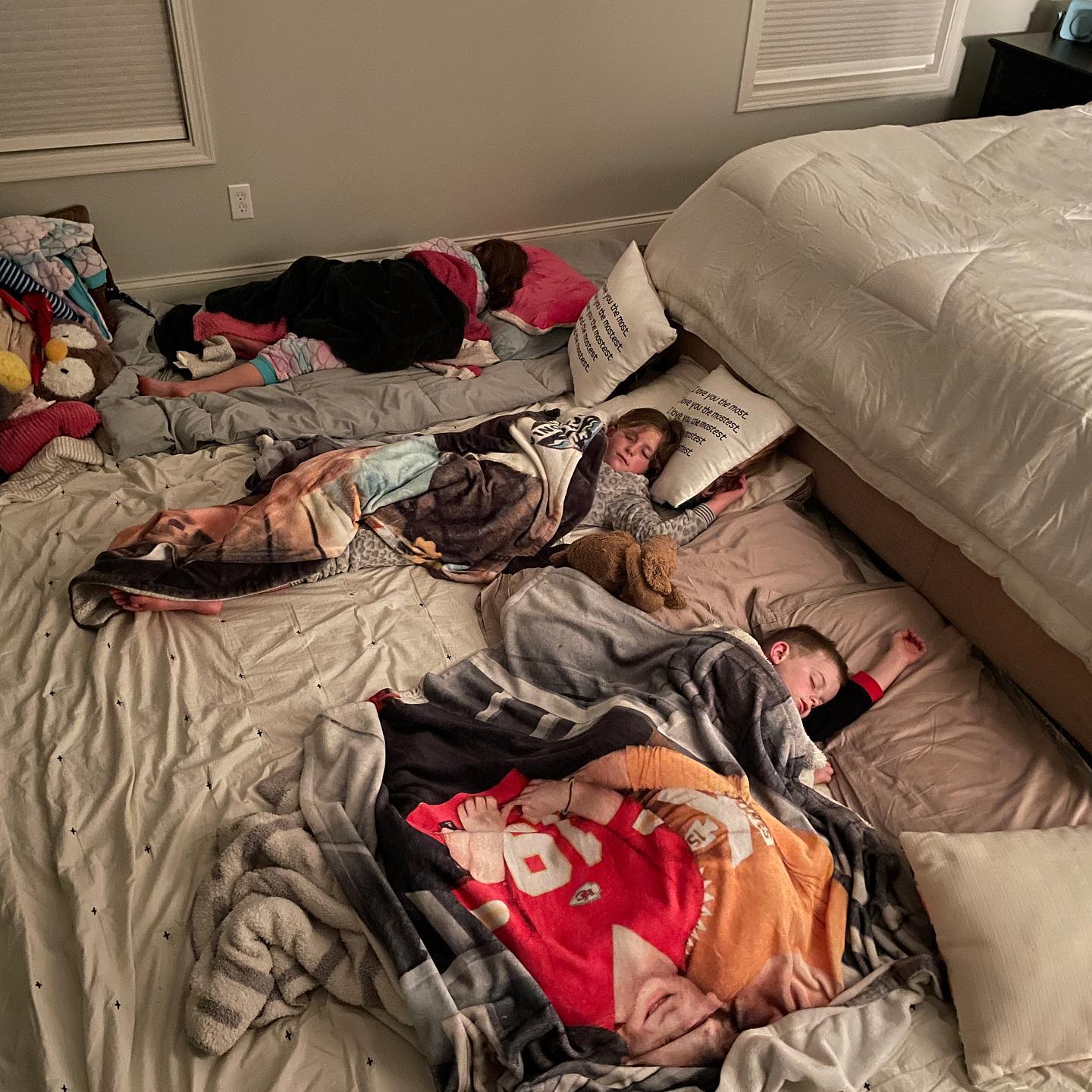 Imagine cu trei copii care dorm pe jos