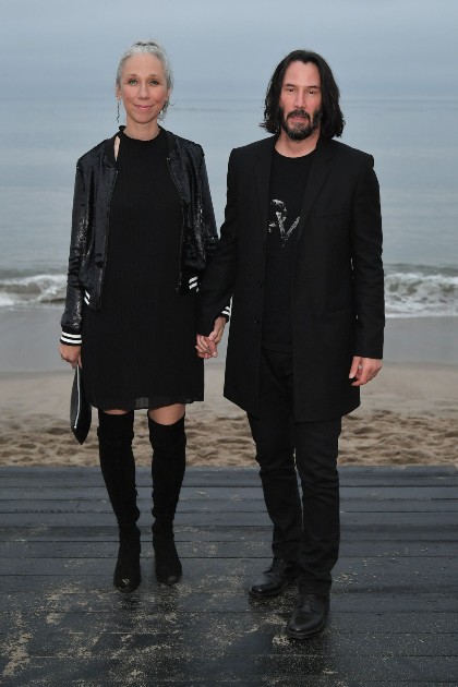 Imagine cu Keanu Reeves și Alexandra Grant îmbrăcați în negru, pe plajă