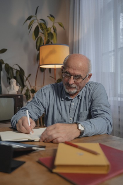 Imagine cu un bărbat bătrân care scrie într-un caiet