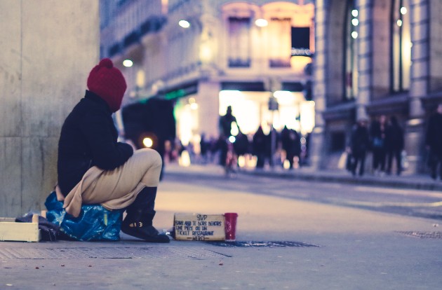 Imagine cu un bărbat fără adăpost care stă pe stradă