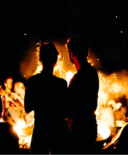 Imagine cu un bărbat și o femeie care stau în fața focului