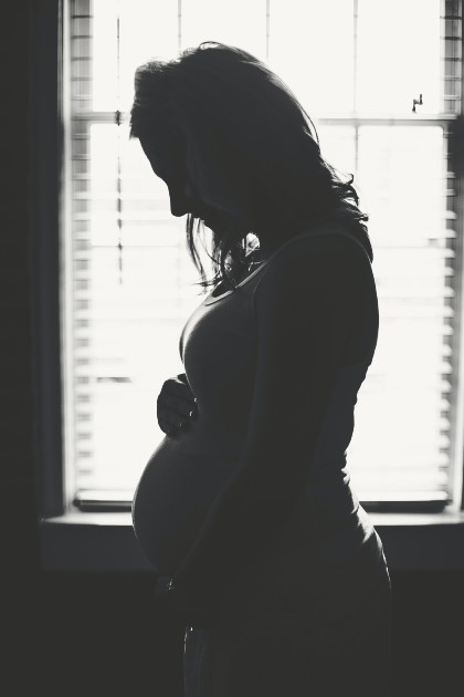 Imagine alb-negru cu o femeie gravidă care își ține mâinile pe burtă