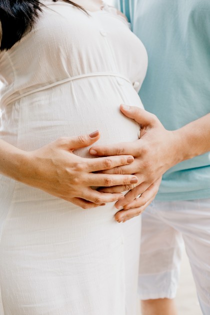 Imagine cu o femeie gravidă alături de un bărbat care o mângâie pe burtă