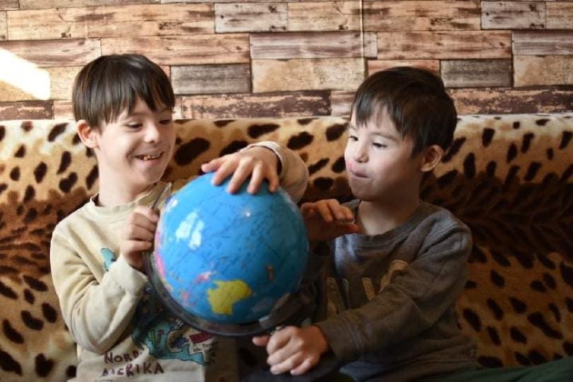 Imagine cu gemenii Cristinei Bălan în timp ce se joacă cu un glob