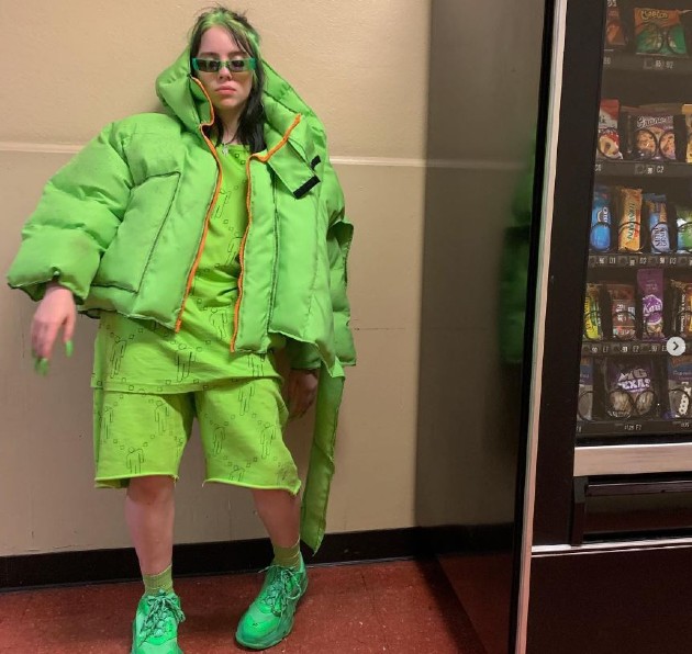 Imagine cu Billie Eilish îmbrăcată în haine largi, verzi