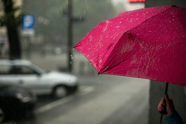 Imagine cu o femeie care ține o umbrela roz în mână