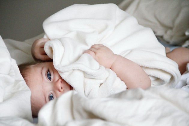 Imagine cu un bebeluș acoperit cu o păturică albă