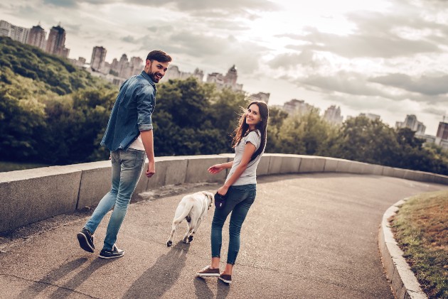 Imagine cu un cuplu care plimbă un câine