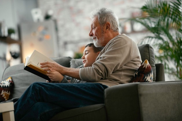 Imagine cu un bunic care îi citește nepotului său povești