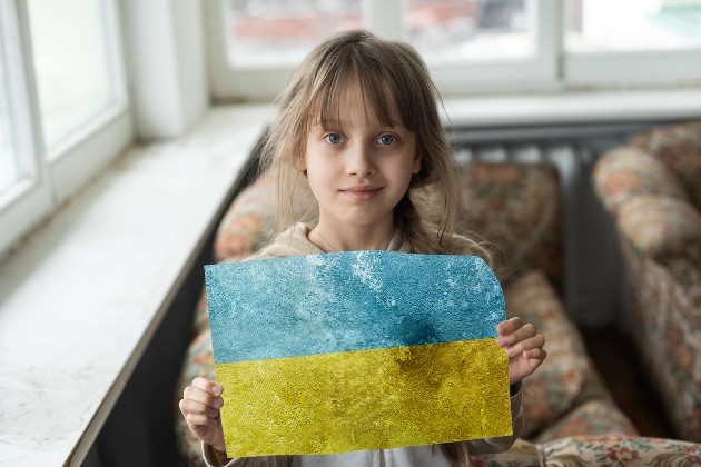 Imagine cu o fetiță care ține în mâini o foaie cu steagul Ucrainei