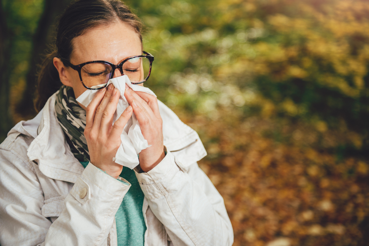 femeie cu alergii care isi sufla nasul