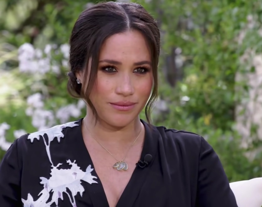 meghan markle priveste fix in lateral, sta asezata pe scaun, in timpul interviului acordat pentru oprah winfrey