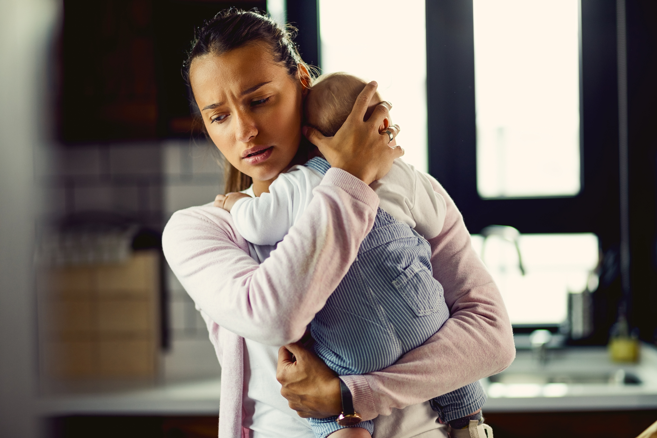  mama priveste ingrijorata in jos, in timp ce isi tine protector bebelusul la piept