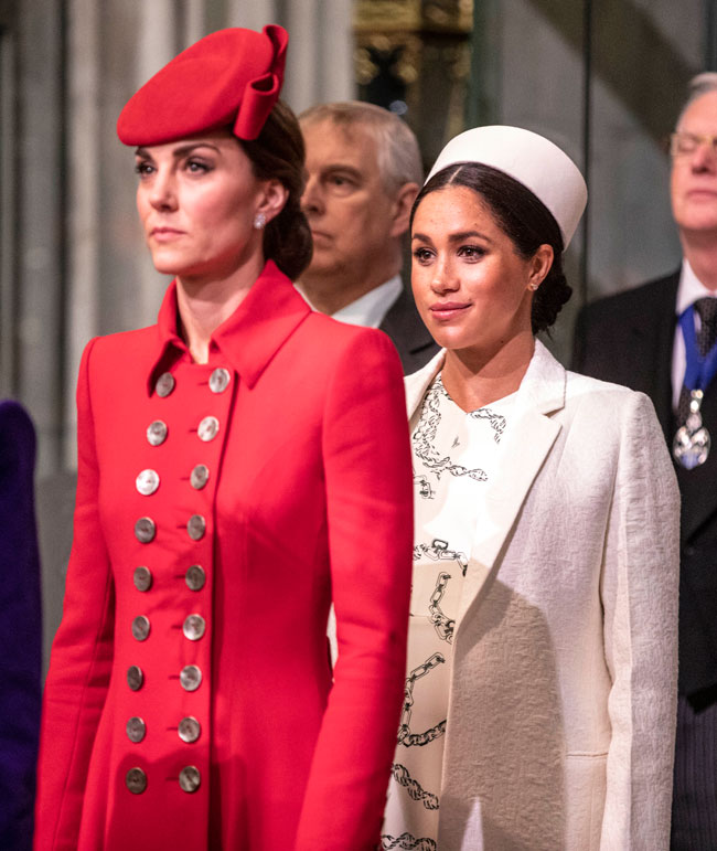 meghan markle si kate middleton, una in spatele celeilalte, privesc in fata, in timpul unui eveniment oficial