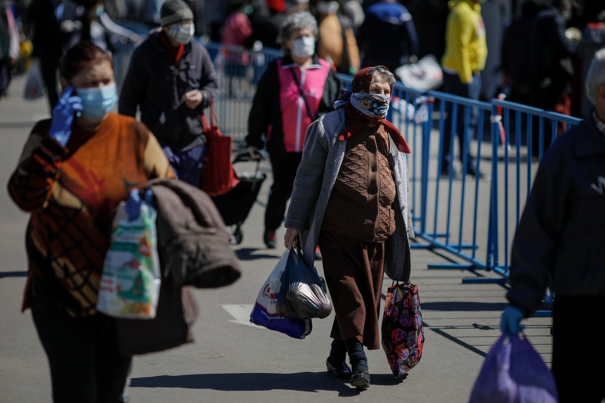 oameni mergand pe strada cu masti de protectie pe fata, in timpul pandemiei de coronavirus