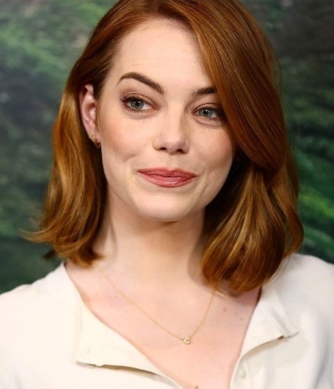 emma stone zambeste subtil in timp ce priveste intr-o parte si sta asezata in picioare