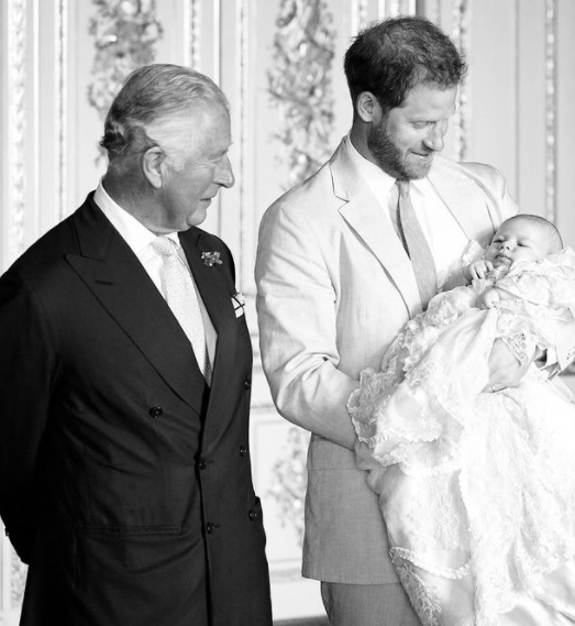 printul charles il priveste pe nepotul sau, archie, care este tinut in brate de tatal sau, printul harry