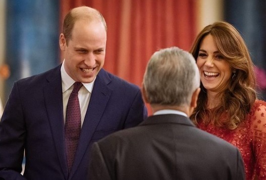 printul william saluta un barbat, iar alaturi de el este kate middleton, care zambeste larg