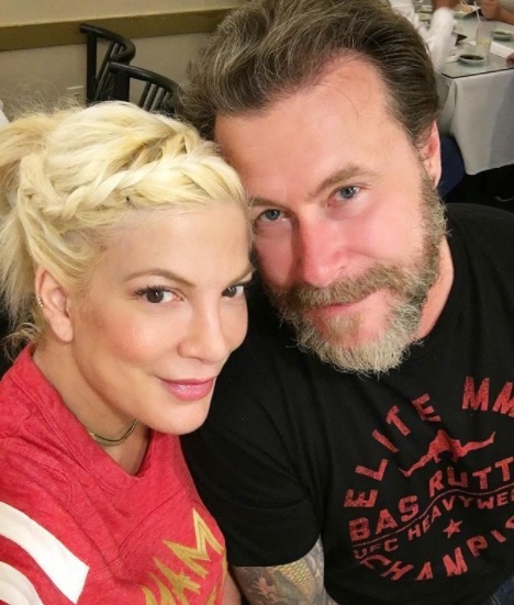 tori spelling si sotul ei stau unul langa celalalt si zambesc