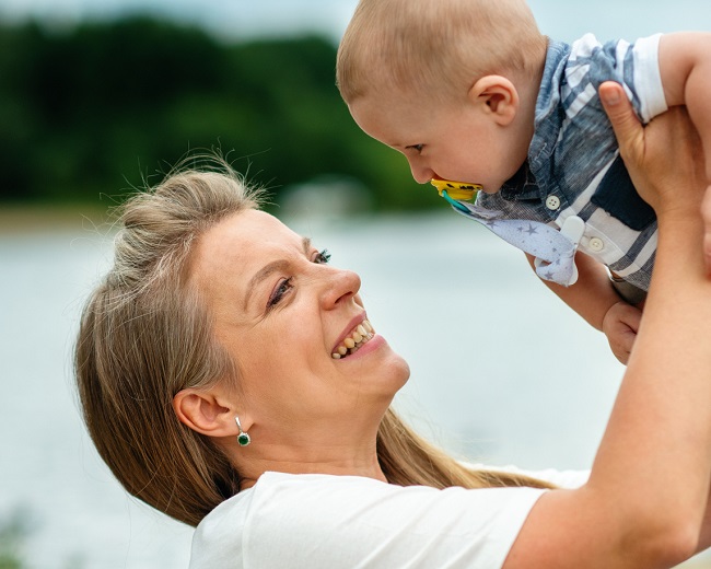 o mama in varsta isi tine copilul in sus si ii zambeste