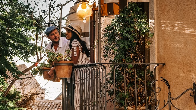 un barbat si o femeie stau la un balcon si vorbesc