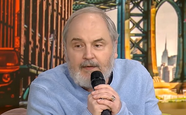 Eugen Cristea invitat la o emisiune TV cu microfon in mana si pulover albastru