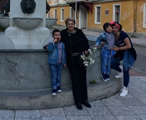 Adriana Bahmuteanu alaturi de mama si de copiii ei langa o fantana intr-un oras