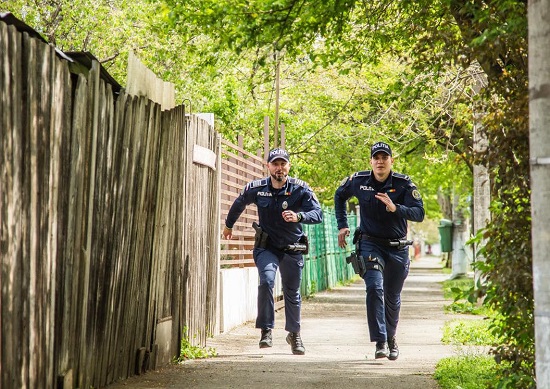 politisti alergand spre o interventie intr-o zona cu case