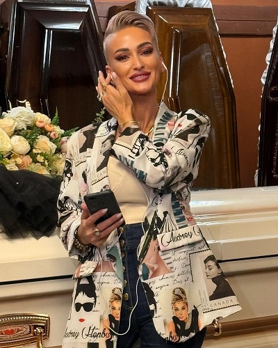 Gabriela Lucuțar, Regina Întunericului, zambind si stand in fata unor sicrie