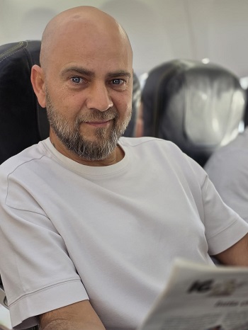 Cosmin Seleși în avion imbracat in tricou alb si citeste un ziar