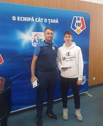 Fabian Căprău impreuna cu un coleg in echipament sportiv si cu un afis sportiv in spate