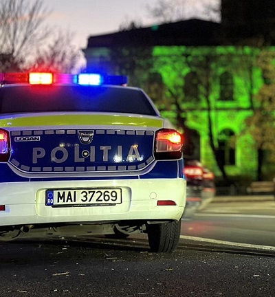 mașină de poliție cu luminile aprinse seara cu o clădire pe fundal