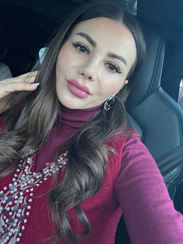 senatoarea POT Valentina Aldea, stand pe scaunul din masina,îmbracata in pulover pe gat si vesta in culoarea fructelor de padure, brodata pe margini cu un ornament cu margele albe 