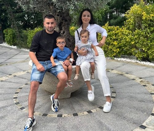 Sara, fetița de 2 ani care a murit la o clinica stomatologica, imbracata intr-o rochita alba cu dungi, alaturi de parintii si de fratele ei, stand pe genunchiul mamei sale