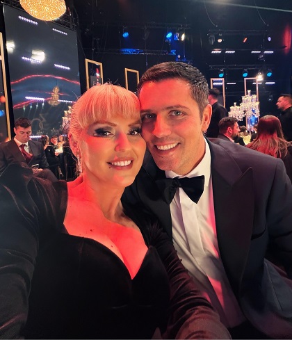 Lucian Viziru imbracat in costum negru cu papion, fericit langa sotia lui, Ema, imbracata in rochie neagra decoltata, participand impreuna la un eveniment festiv in cadrul PRO TV